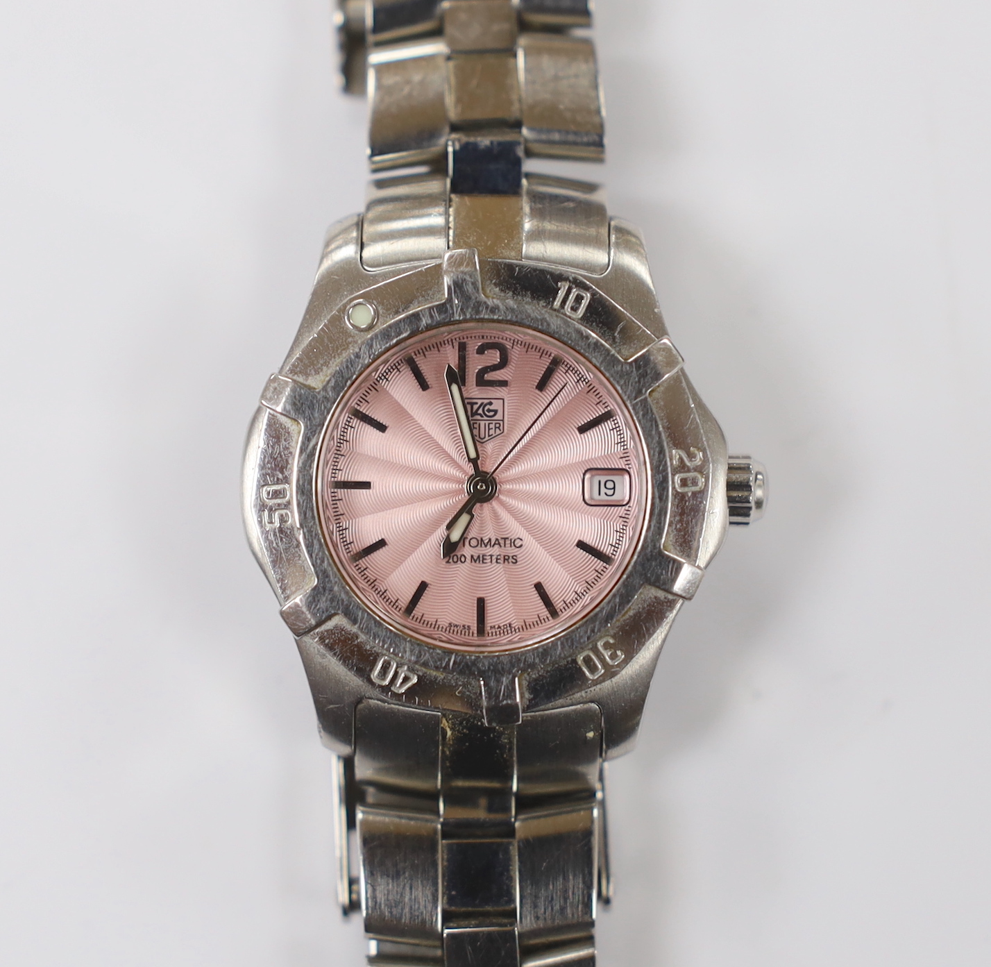 A lady's modern stainless steel Tag Heuer automatic wrist watch, with pink dial, on a Tag Heuer stainless steel bracelet. Condition - fair to poor